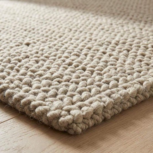 Chunky braided knit rug in neutral beige with thick textured yarn ideal for cozy Nordic interiors