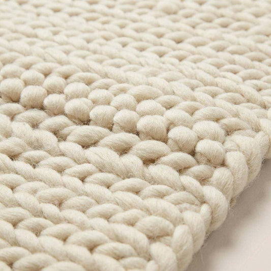 Chunky knit area rug with thick, textured neutral yarn, adding cozy warmth and modern organic style to floors