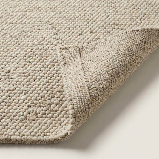 Thick chunky knit area rug with looped wool texture in neutral tones for cozy living room and bedroom decor