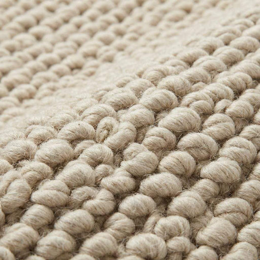 Chunky knit neutral rug with thick oversized loops and warm textured natural fibers for cozy Scandinavian interiors
