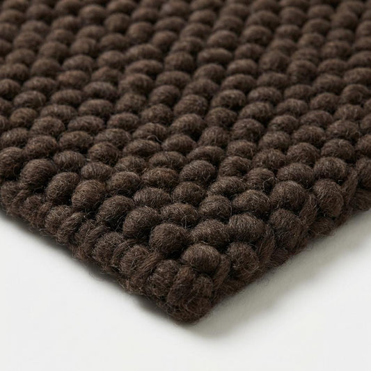 Chunky knit rug in dark brown with thick braided roving texture for cozy modern organic interiors