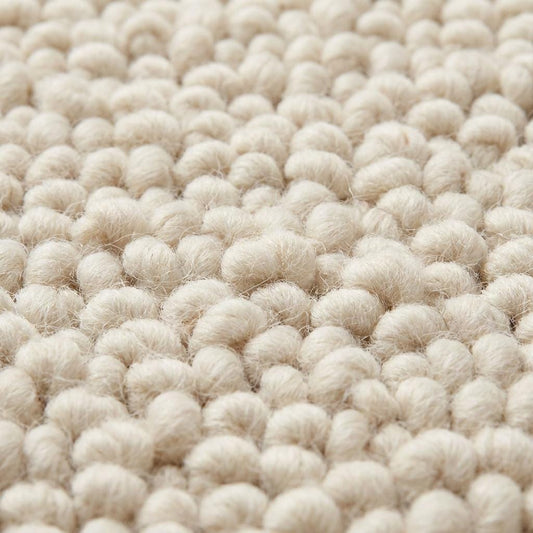 Handwoven chunky knit wool rug in soft ivory with thick loops, perfect cozy minimalist living room carpet