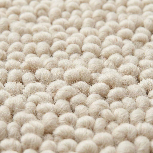 Handwoven chunky knit wool rug in soft ivory with thick loops, perfect cozy minimalist living room carpet