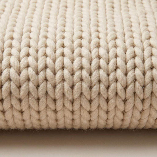 Neutral beige chunky knit wool rug with thick braided texture for cozy Scandinavian minimalist living room decor