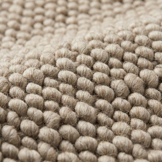 Chunky knit wool rug with thick oversized loops in neutral tone for cozy Scandinavian home decor