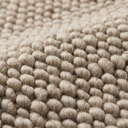 Chunky knit wool rug with thick oversized loops in neutral tone for cozy Scandinavian home decor