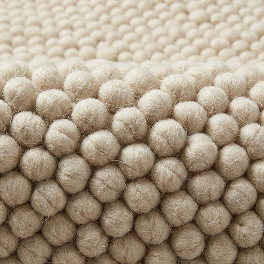 Chunky knit wool rug in ivory with thick braided texture and soft natural fibers for cozy neutral decor