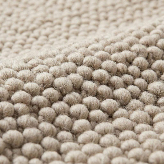 Cream minimalist textured rug surface highlighting dense looped yarn pattern