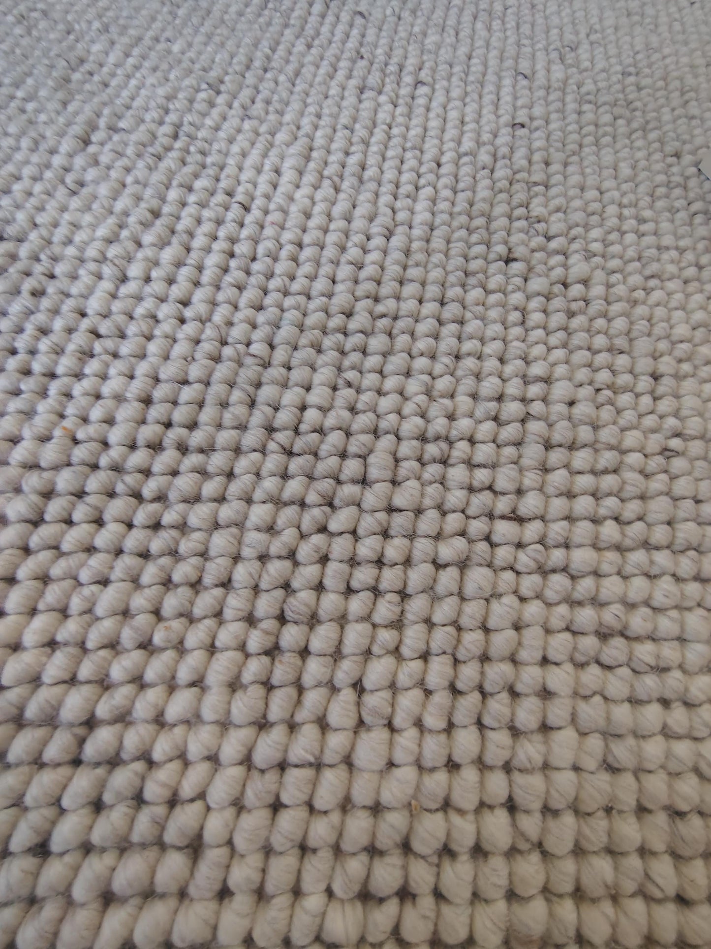 Chunky looped ivory rug with thick textured loops and neutral minimalist design on hardwood floor