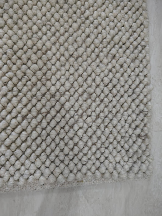 Chunky looped ivory rug with thick textured yarn and neutral minimalist design on hardwood floor