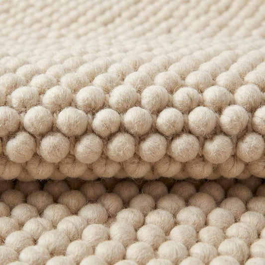Chunky textured neutral area rug with thick looped plush surface in cozy living room setting