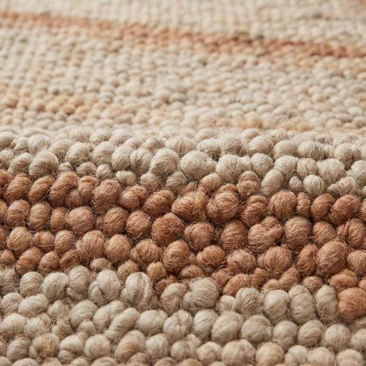 Close-up of thick pebble-textured wool rug with warm earthy stripe detail
