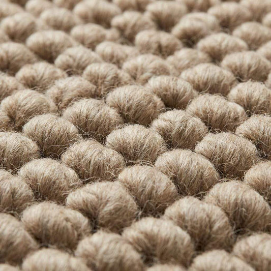 Chunky wool area rug with thick, braided neutral beige texture in living room.