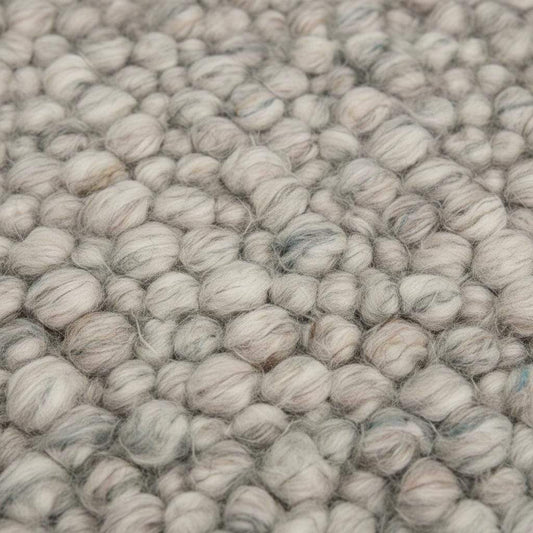Handmade natural wool rug with thick pebble texture, beige and ivory fibers, ideal for modern minimalist living room décor.
