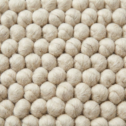 Handwoven chunky wool rug with textured weave, minimalist Scandinavian home interior style