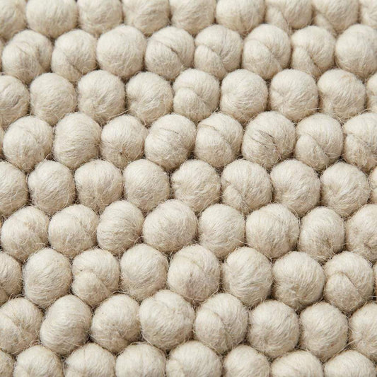 Handwoven chunky wool rug with textured weave, minimalist Scandinavian home interior style