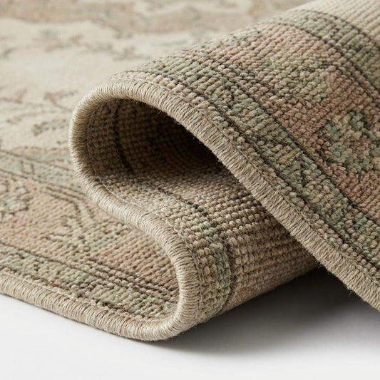 Close up of hand knotted wool rug pile showing individual knots, soft sheen, and distressed vintage-style texture.