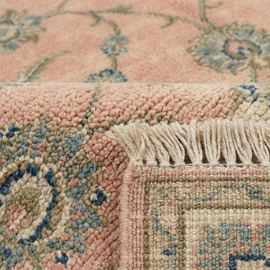Close up of hand knotted wool pile showing individual knots and soft floral vine pattern.