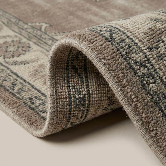 Close up of hand knotted wool pile showing tight weave structure and distressed vintage finish.