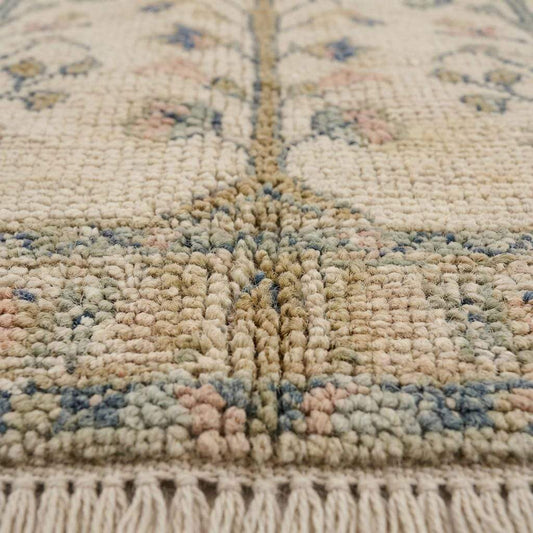 Close up detail of hand knotted wool pile texture, showing individual knots, organic fiber irregularities, and soft antique wash finish.