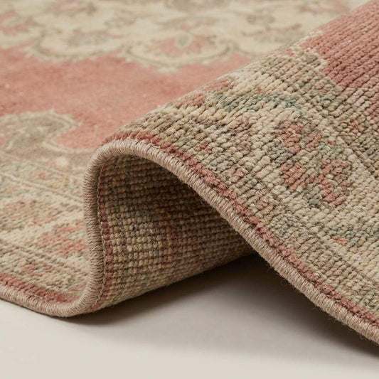 Close up of hand knotted wool rug showing natural pile texture, knot structure, and soft vintage finish