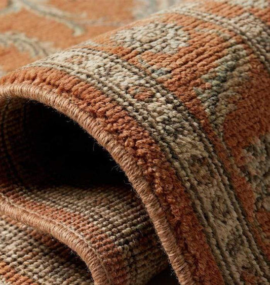 Close-up texture of a hand-knotted wool rug showing individual knot structure, low pile height, and intricate cream and olive green floral weaving.