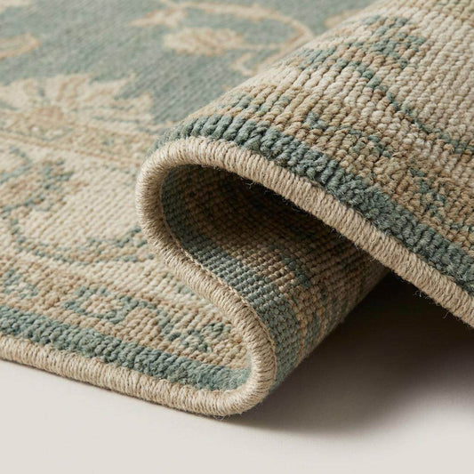 Close-up of hand knotted wool rug showing low pile texture and individual knot structure