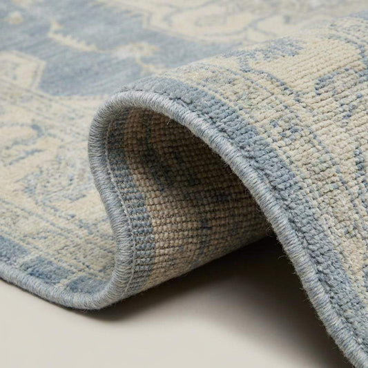 Close-up of dense hand knotted wool pile showing individual knots, soft vintage wash, and natural fiber texture