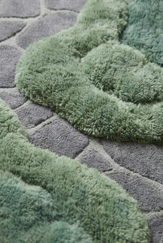 Close-up of dense wool tufted pile showing raised moss-like texture and carved stone pattern detail