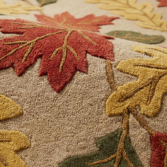 Hand tufted wool rug with autumn leaf pattern in rust, mustard, and olive tones on beige background