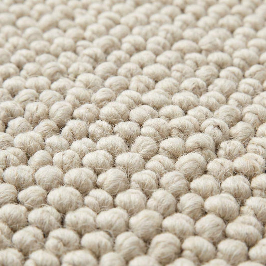 Handwoven chunky wool rug with textured loops in neutral cream tones for Scandinavian decor