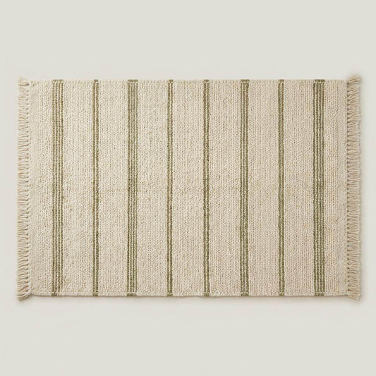 Handwoven wool area rug with chunky knit, green stripes, and tassels on neutral cream background