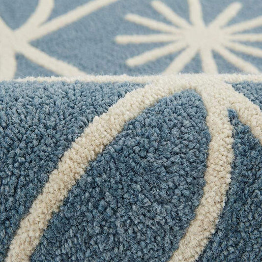 Close-up detail of plush blue and cream geometric rug showing raised tufted starburst pattern, dense fibers, and soft textured pile craftsmanship