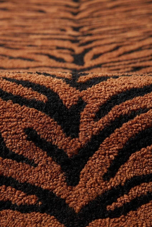 Close-up of plush hand tufted rug pile showing dense yarn loops and black tiger stripe pattern on orange background __etsy:7803998776