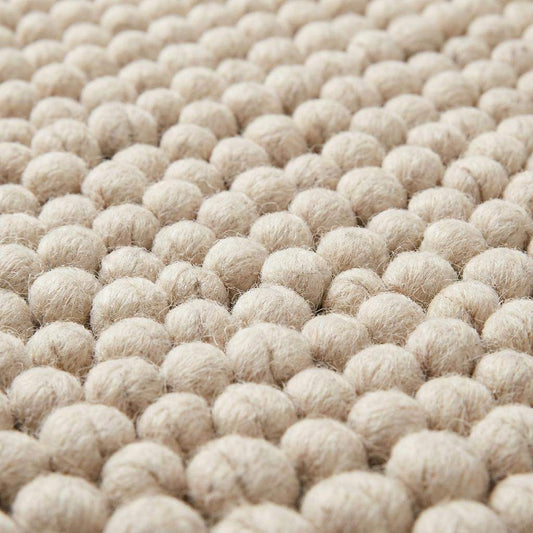 Handmade chunky wool rug with felt ball texture in neutral beige and cream tones for modern farmhouse decor