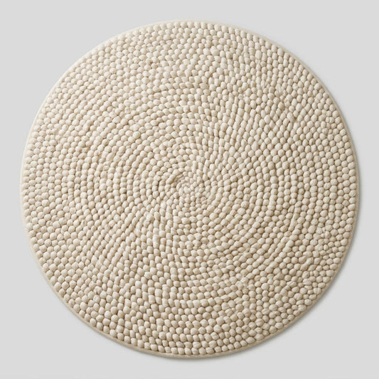Chunky Wool Rug in cream ivory, with a round shape and thick, handwoven pebble-like coils forming a spiral pattern.