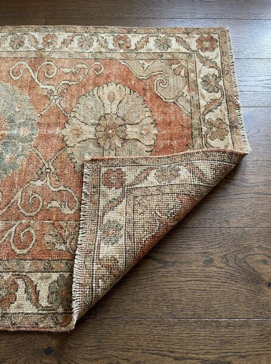 Hand knotted vintage Oushak runner rug with floral medallion and lion motif in terracotta pink and beige wool
