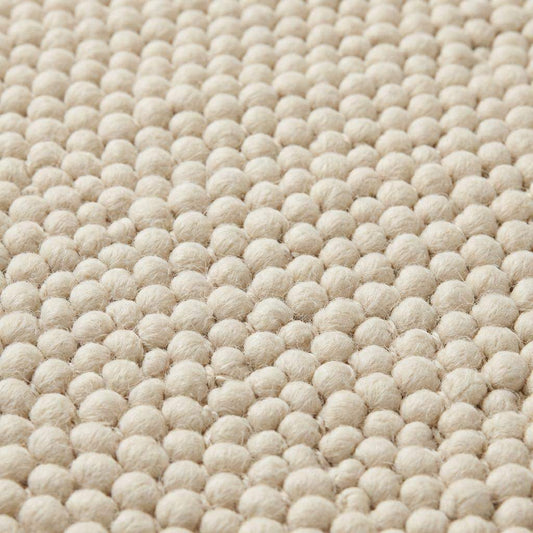 Handmade chunky wool rug with neutral tones in Scandinavian minimalist living room setting