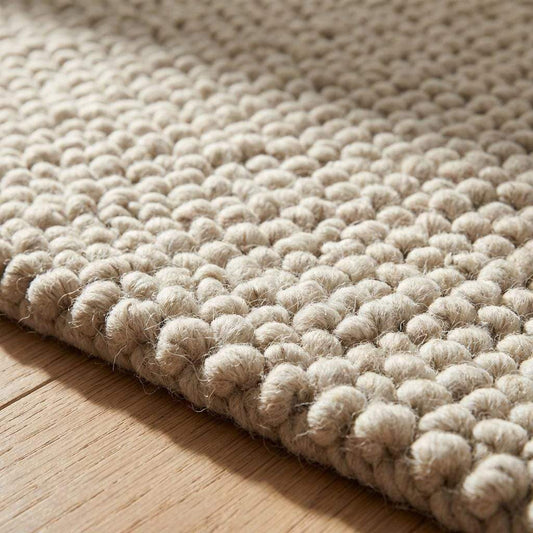 Handmade chunky wool rug with thick textured natural fibers in neutral tones for cozy minimalist living room decor