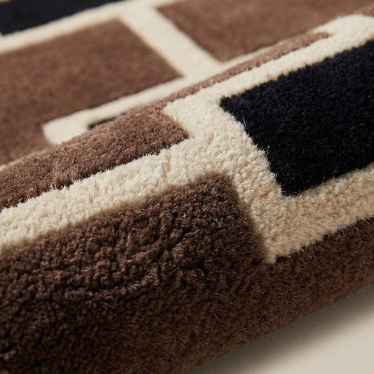 Close-up of hand tufted wool rug pile showing dense cut pile texture with carved geometric pattern lines in brown and ivory wool fibers __etsy:7789914452