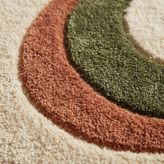 Close-up of plush tufted abstract rug texture showing soft high-pile fibers in cream, terracotta and olive tones, detailed craftsmanship and dense woven surface.