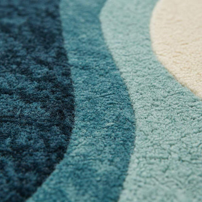 Blue wavy abstract area rug with coastal blues and teals in a modern living room setting