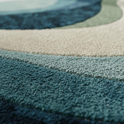 Blue wavy abstract area rug with layered blues and teals in a modern coastal living room setup