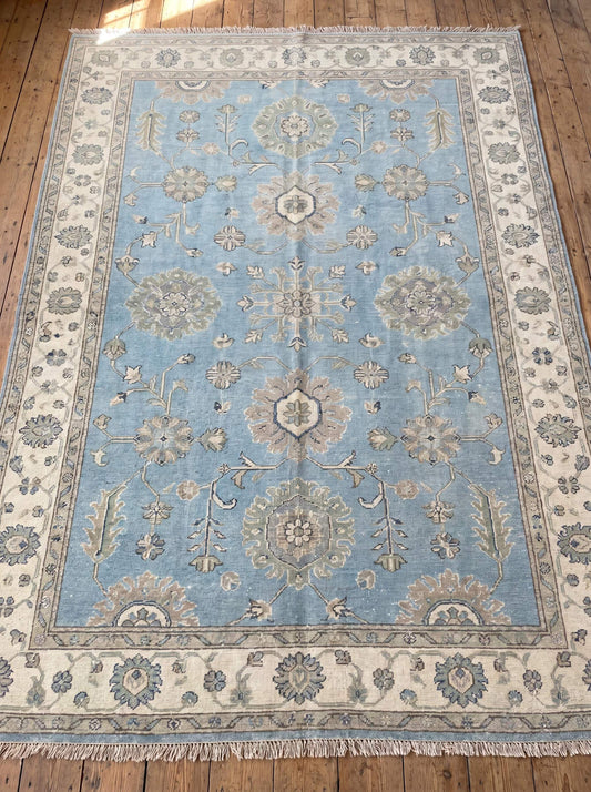 Hand knotted Oushak rug featuring soft blue field, floral motifs, and ivory border for elegant living room décor __etsy:8133057955