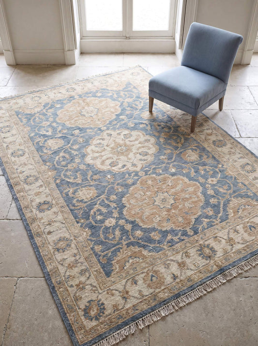 Hand knotted Oushak rug in dusty blue and beige with vintage floral medallion design placed in a bright living room __etsy:8110186829