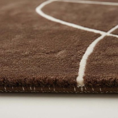Modern brown abstract rug with curved white lines and hand tufted design