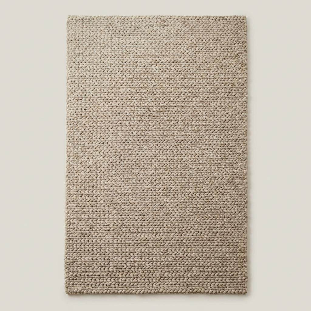 Chunky braided knit rug in neutral beige with thick textured yarn, ideal for cozy Nordic interiors and warm minimalist spaces