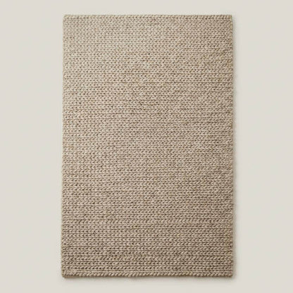 Chunky braided knit rug in neutral beige with thick textured yarn, ideal for cozy Nordic interiors and warm minimalist spaces