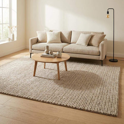 Chunky braided knit rug in neutral beige with thick, textured yarn for cozy Nordic interiors
