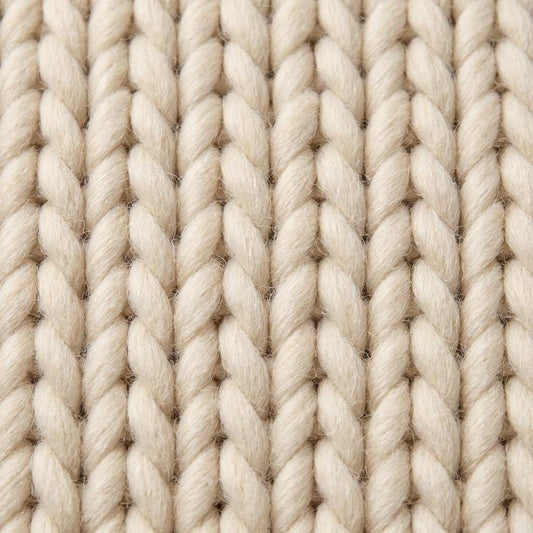 Detailed view of braided rug edge with oversized yarn strands and dense textured weave